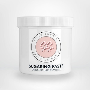 May include: A white cylindrical plastic jar with a screw-top lid. The label features a circular logo with the text Silky Smooth Sugaring Paste and the letters SS in the centre. Below the logo, the text reads Sugaring Paste Organic Hair Removal.
