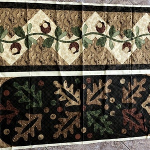 May include: Two decorative fabric panels with a quilted design. The top panel features a floral vine pattern with brown flowers and green leaves on a cream and tan background. The bottom panel has a black background with leaf and dot patterns.