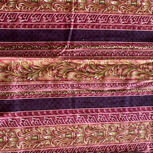 May include: A fabric featuring a repeating horizontal pattern of dark purple bands alternating with ornate decorative stripes in shades of red, gold, and olive green. The design includes intricate scrolling acanthus leaf motifs.