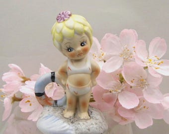 Adorno vintage para tarta de cumpleaños de verano de Enesco: Niña con salvavidas, belleza playera, arena y olas.