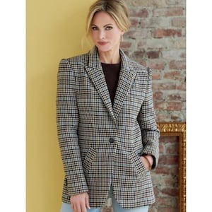 May include: A plaid blazer in a classic pattern of black, tan, and light blue. The blazer has a single-button closure, two front pockets, and a notched lapel. The model is wearing a brown top and light blue jeans.