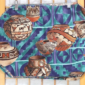 May include: A fabric item with a repeating pattern of Southwestern pottery designs in shades of brown, orange, and cream, set against a teal and purple geometric background. The pottery features detailed illustrations of animals and geometric shapes.