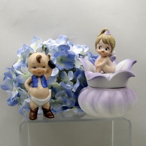 May include: A set of three ceramic mugs with a speckled, matte finish. The mugs are in shades of cream, light brown, and dark brown. Each mug has a simple, minimalist design and a rounded handle.