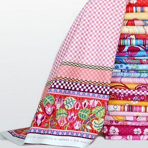May include: A stack of colorful fabric bolts with a patterned design. The fabric on the left has a pink checkered pattern and a floral border with the text "by LILLI GIBSON for oliver + s". The stack includes various floral and geometric patterns.