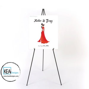 May include: A white wedding sign with a black easel stand. The sign features a cartoon illustration of a bride and groom in traditional Chinese wedding attire. The text on the sign reads "Katie & Tony" and "July 20, 2016".