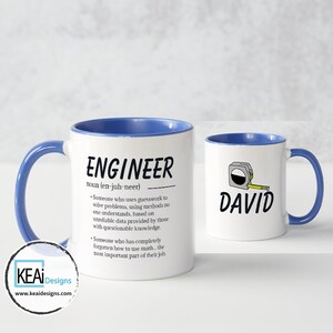 May include: White ceramic mug with a blue rim and handle. The mug features a definition of the word "Engineer" with a humorous description. The second mug is white with a blue rim and handle and features a cartoon measuring tape with the name "David" written below it.