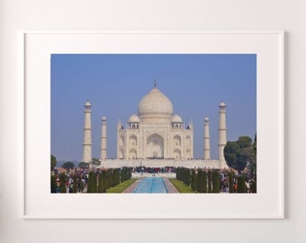 May include: A framed print of the Taj Mahal, a white marble mausoleum, set against a clear blue sky. The image is displayed above a white sofa with decorative cushions. The text "PRINTABLE WALL ART" is displayed on the image.