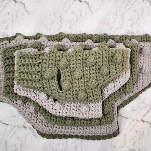 Op de afbeelding: Een set van vier gehaakte hondenbandanas in groen en grijs. De bandanas zijn op elkaar gelegd, met de groene bandanas bovenop en de grijze bandanas onderaan.