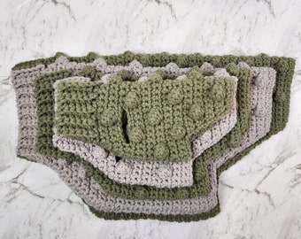 May include: A set of four crocheted dog bandanas in green and gray. The bandanas are layered on top of each other, with the green bandanas on top and the gray bandanas on the bottom.