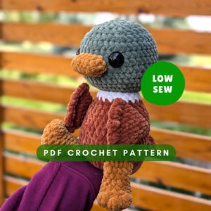May include: Crochet pattern for a plush toy duck with a green head, brown body, and orange beak. The pattern is labeled "Low Sew" and "PDF Crochet Pattern".