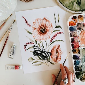 Puede incluir: Una pintura de acuarela de una mariposa y flores. La mariposa es negra y blanca con un patrón rayado. Las flores son rosas y rojas con hojas verdes. La pintura está sobre un fondo blanco.