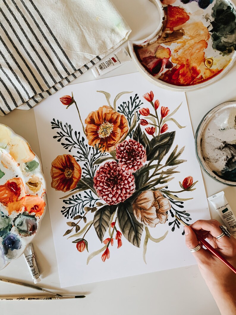 May include: A watercolour painting of a floral bouquet featuring orange, red, and pink flowers. The painting is on a white background and is being worked on by an artist.