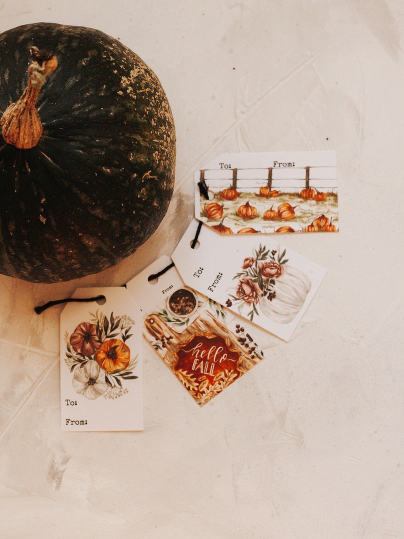 May include: Four fall-themed gift tags with handwritten text that reads "To:" and "From:". The tags feature illustrations of pumpkins, gourds, and fall foliage. One tag has the text "hello fall" in red.