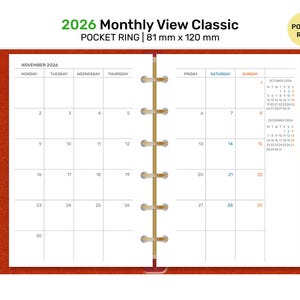 May include: Open planner with a monthly view for November 2025, featuring a calendar grid. The planner is labeled "2026 Monthly View Classic" and "Pocket Ring" with dimensions of 81 mm x 120 mm. The cover is a reddish-orange color.