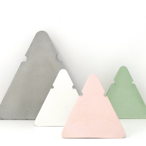 Peut inclure: Quatre étagères en béton de forme triangulaire de différentes tailles et couleurs. La plus grande étagère est grise, la suivante est blanche, la suivante est rose et la plus petite est verte.