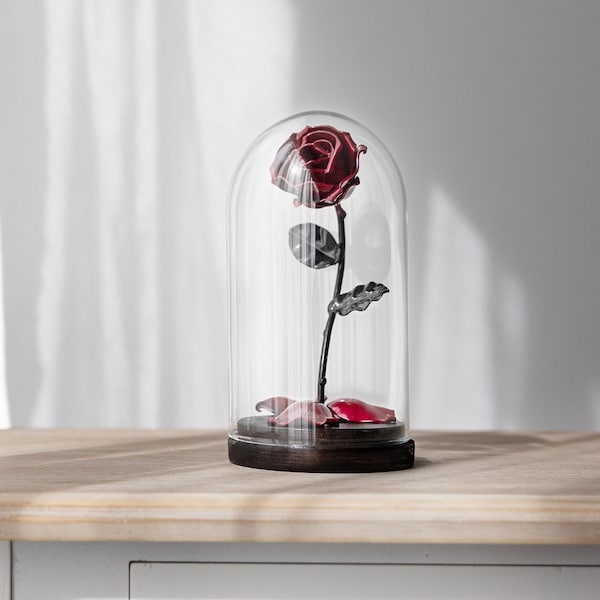 Rose La belle et la Bête à pétales rouge tombés et en dôme de verre sur socle en bois