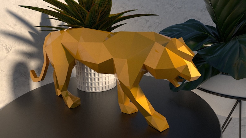 May include: A gold-colored, geometric, origami-style sculpture of a tiger. The sculpture is standing on a black table with a green plant in a white pot in the background.