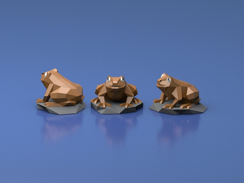May include: Three brown origami frogs sitting on gray rock bases. The frogs are in different poses, one facing forward, one facing to the left, and one facing to the right.