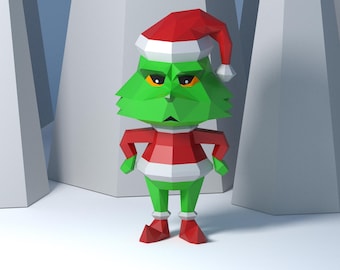 Puede incluir: Una figura geométrica verde del Grinch con un gorro de Papá Noel rojo y blanco y un atuendo a juego. La figura tiene una expresión de enfado y está de pie frente a un fondo blanco y gris.