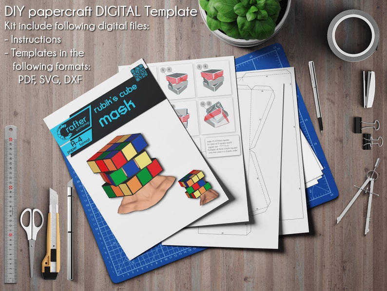 Pode incluir: Um modelo digital de papercraft para uma m&aacute;scara de cubo de Rubik. O modelo inclui instru&ccedil;&otilde;es e arquivos nos formatos PDF, SVG e DXF. A imagem mostra uma m&aacute;scara de cubo de Rubik colorida, uma r&eacute;gua, um tapete de corte, um compasso e um l&aacute;pis.