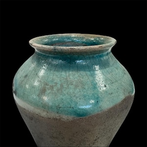 Könnte beinhalten: Eine handgefertigte Keramikvase mit einem breiten, abgerundeten Körper und einem leicht ausgestellten Rand. Die Vase hat ein zweifarbiges Farbschema mit einem türkisfarbenen oberen Bereich und einem gedämpften graubraunen unteren Bereich. Die Oberfläche hat eine Craquelé-Textur.