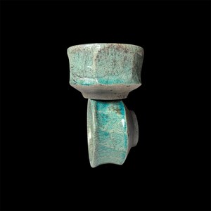 May include: Two teal ceramic teacups with a crackled glaze. The cups are stacked on top of each other.