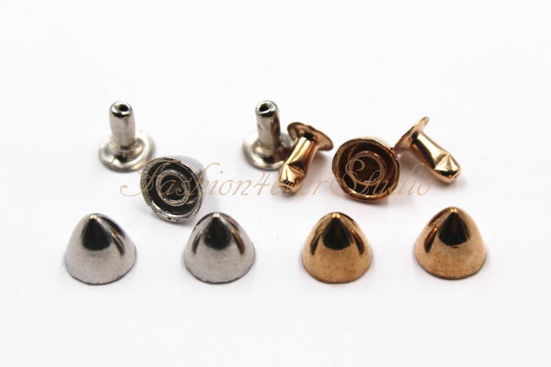 May include: A collection of metal cone studs in silver and gold tones. The studs have a conical shape with a flat base and a post for attachment. Some studs have a decorative spiral design.