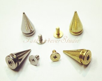 Könnte beinhalten: Ein Satz mit vier Metall-Pyramidennieten mit Schraubrücken. Zwei Nieten sind silberfarben und zwei sind goldfarben.