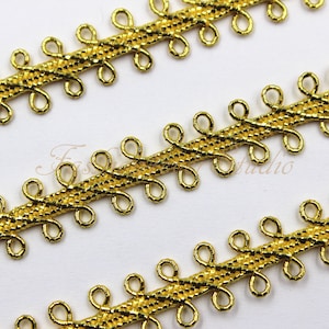 Puede incluir: Adorno dorado con textura tejida y detalles en bucle. El adorno tiene un acabado brillante.