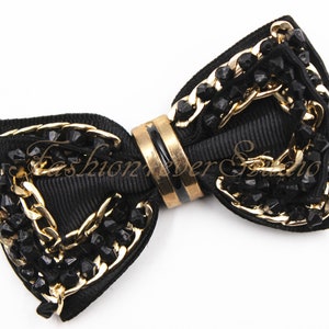 May include: Black bow tie with gold chain and black bead embellishments.