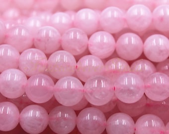May include: A strand of pink rose quartz beads. The beads are round and smooth, with a translucent appearance.