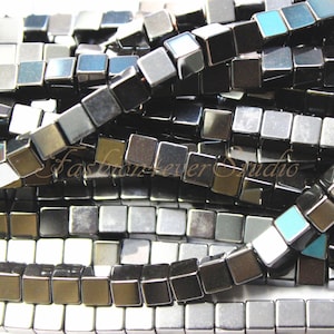 May include: A strand of black and silver square beads. The beads are faceted and have a metallic sheen.