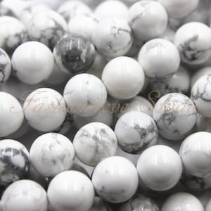 May include: A strand of white howlite beads with grey veining. The beads are round and smooth, and they are strung on a clear thread.