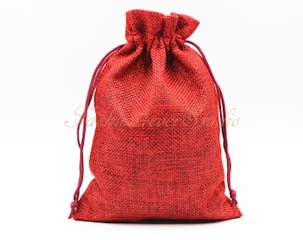 May include: A red drawstring bag made of burlap fabric. The bag is empty and has a white background.