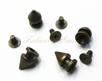 Könnte beinhalten: Ein Satz mit sechs antiken goldfarbenen Metallpyramiden-Nieten mit Schraubrücken. Die Nieten sind etwa 2,5 cm lang.