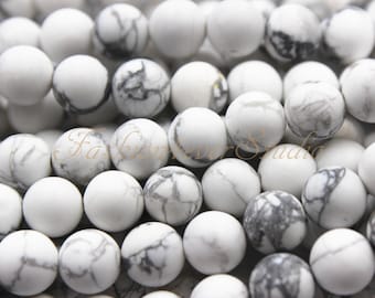 May include: A close-up of a pile of white and gray round beads. The beads are made of natural stone and have a smooth, polished finish.