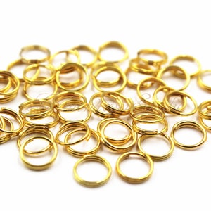 以下が含まれることがあります： たくさんの金色のジャンプリングの山。リングはすべて同じサイズで、金属製です。