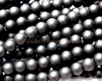 May include: A close-up image of a pile of black matte round beads. The beads are smooth and have a slightly shiny finish.