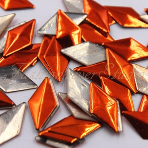 May include: A pile of orange and silver metallic diamond-shaped embellishments.