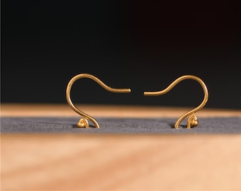 May include: A pair of gold-toned earring hooks with a small ball at the end of each hook.