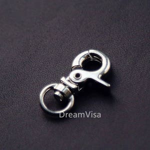 May include: Silver swivel clasp with a round ring. The clasp is made of metal and has a polished finish.