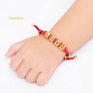 May include: Red string bracelet with gold beads spelling out the word "LOVE".