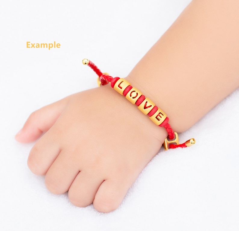 May include: Red string bracelet with gold beads spelling out the word "LOVE".