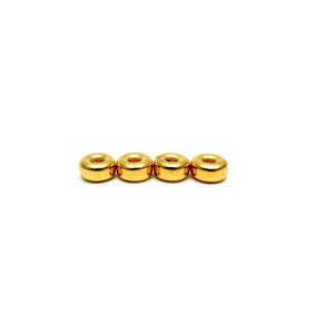 May include: Four gold-colored metal beads in a row. The beads are round with a hole in the center.