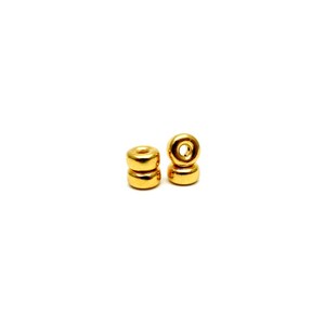 May include: Two gold-colored metal beads with a hole in the center. The beads are stacked on top of each other.