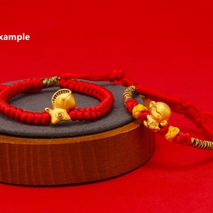 May include: Two red string bracelets with gold charms. One charm is a horse and the other is a monkey.