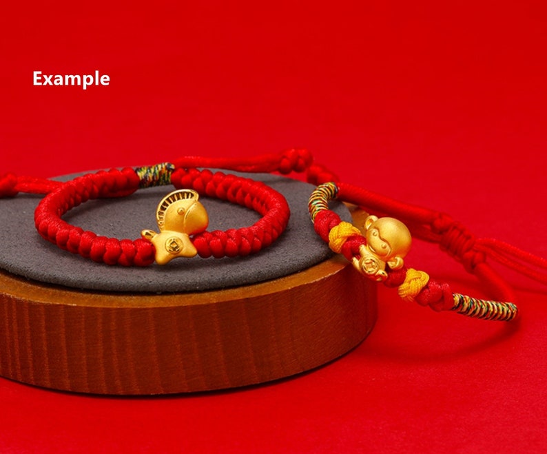 May include: Two red string bracelets with gold charms. One charm is a horse and the other is a monkey.