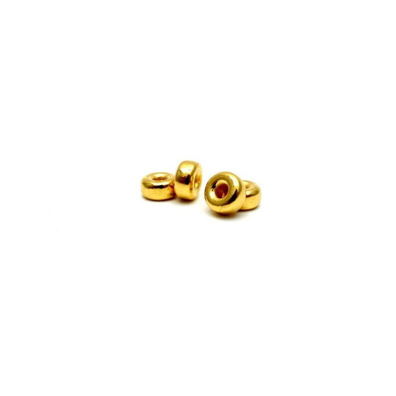 May include: Four gold-colored metal beads, each with a round shape and a hole in the center.