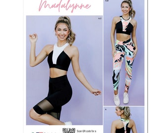 May include: Simplicity sewing pattern S9620 featuring Madalynne designs. The pattern includes a sports bra and leggings. The sports bra is black and white. The leggings have a colorful abstract pattern. The text "Designed and printed in USA" is visible.