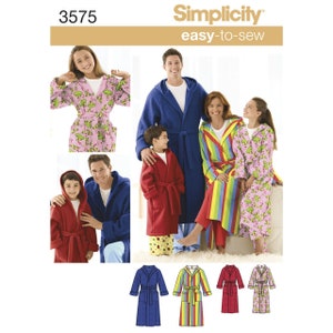 Peut inclure: Patron de couture Simplicity facile à coudre présentant des peignoirs à capuche de différentes couleurs et motifs. Les peignoirs comprennent des modèles unis bleus, rouges et à rayures arc-en-ciel, ainsi qu'un peignoir rose à motif de grenouilles. Le patron inclut des tailles pour toute la famille.